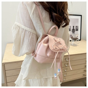 Detailed back view of a pink bow ballet-style backpack worn by a model in a minimalist room