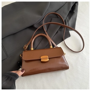 Close-up of vintage brown leather handbag with bronze metal clasp and slim shoulder strap