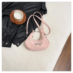 Detailed close-up of a pink half-moon bag with a silver metallic bow and chain strap