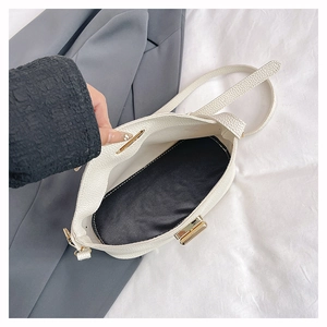 Detail of white lychee leather bucket bag showing golden twist lock and black interior