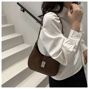 Detail of vintage brown leather underarm bag with silver buckle on a minimalist model
