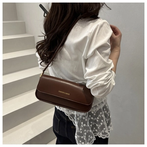 Side view of a vintage brown rectangular baguette bag on a model's shoulder in a minimal setting