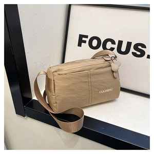 Detail of khaki nylon crossbody bag showing the embroidered logo and front stitching
