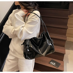 Detail of black glossy PU leather tote bag with drawstring texture and thin shoulder straps