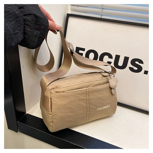 Detail view of khaki minimalist nylon crossbody bag with wide woven strap and multi-zipper layers