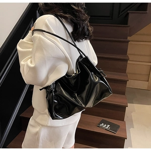 Detail view of large black glossy tote bag with stylish side-knot design and slim straps