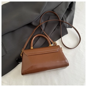 Detail of vintage brown leather handbag featuring retro gold hardware and top handle