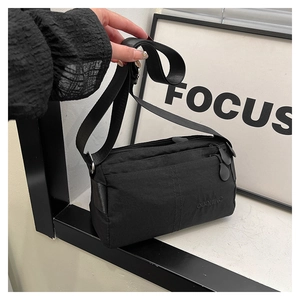 Detail of lightweight black multi-layer nylon crossbody bag with adjustable strap