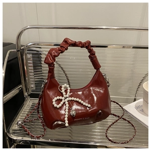 Close-up of wine red bag with pearl bow charm and wrinkled handle detail