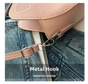 Detail of silver-tone metal hooks and stitching on a light pink faux leather handbag
