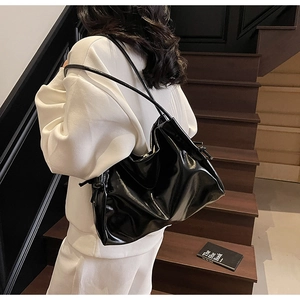 Close-up of black glossy leather tote bag with stylish knot detail on the shoulder strap