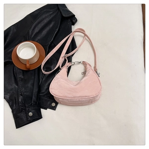 Detailed close-up of pink crescent shoulder bag with adjustable strap and metal handle