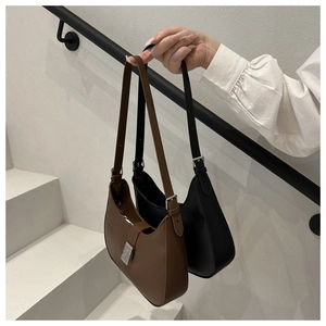 Detail of minimalist half-moon underarm bags in brown and black matte leather