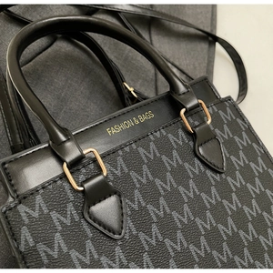 Nahaufnahme der schwarzen Handtasche mit Goldprägung und Monogramm auf Kunstleder