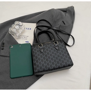 Detail of black crossbody bag with M-letter print and fashion logo on business backdrop