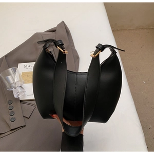 Detail of black matte leather hobo bag with gold buckle on a grey blazer outfit