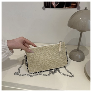 Detailaufnahme der beigen gewebten Umschlagtasche mit Silberkette und Perlenbesatz