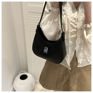 Detail of minimalist black leather hobo bag with silver square buckle and smooth texture