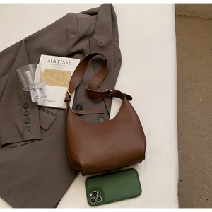 Detailed shot of retro brown leather bag with golden buckle on minimalist fabric