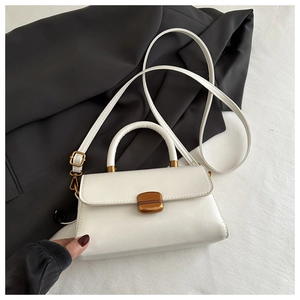 Close-up of textured white faux leather bag with gold buckle on black and white background