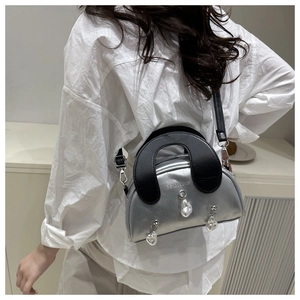 Detail of silver shell bag with black handle and heart-shaped metal charms for women