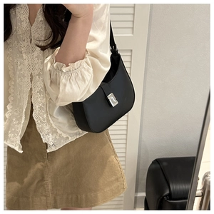Side view of a vintage black leather crescent shoulder bag with silver buckle on a model