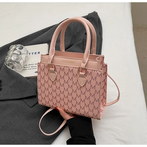 Detailaufnahme der rosa Umhängetasche mit M-Muster-Struktur und goldener Hardware
