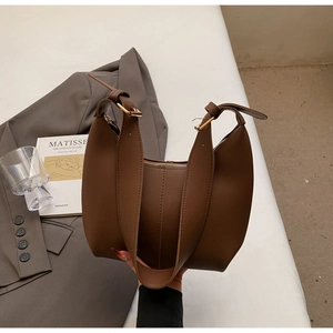 Detail of coffee hobo bag with adjustable straps and gold buckles in a lifestyle setting