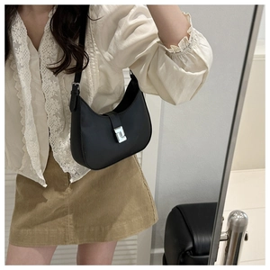 Detail of black crescent shoulder bag with silver buckle worn with lace shirt