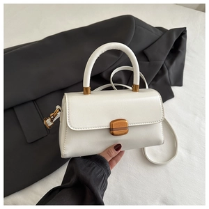 Detail of white mini square bag with vintage bronze metal buckle and smooth top handle