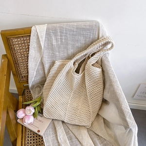 Beige crochet knit tote bag with hollow out design on a vintage chair with flowers