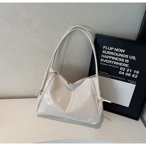 Detail of a creamy beige tote bag featuring drawstring side ties and glossy faux leather texture