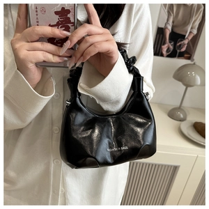 Detail of black glossy pleated handbag with cloud handle and silver zipper detail