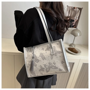 Detail view of silver tote bag with butterfly prints and elegant tassel on shoulder