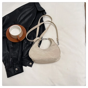 Detail of off-white hobo bag showing wrinkled fabric and silver metallic hardware