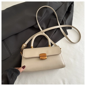 Detail of a beige rectangular handbag featuring a gold curved metal clasp and matte texture