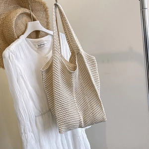 Beige hollow knit tote bag with mesh texture hanging in a summer vacation scene
