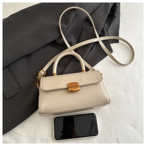 Detail view of beige crossbody bag with gold buckle and smartphone for size reference