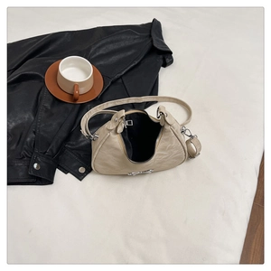 Detail showing cream crescent shoulder bag with silver metallic bow and faux leather texture