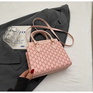 Detailaufnahme der rosa Monogramm-Umhängetasche mit goldener Hardware auf Sakko