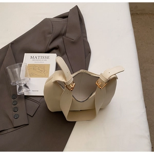Close-up of minimalist cream leather tote bag with adjustable metallic buckle detail
