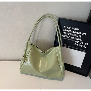 Detail of light green glossy tote bag featuring unique knot decoration on the shoulder strap