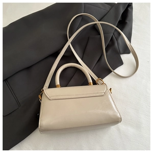 Detail shot of vintage cream faux leather texture and bronze metal hardware on a square bag