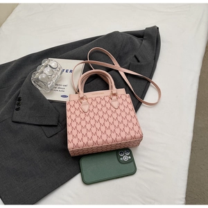 Detailansicht der rosa Umhängetasche mit Monogramm-Muster auf grauem Blazer