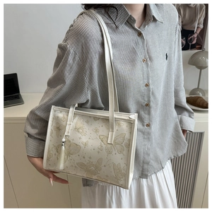 Detail der beigen Vintage-Tragetasche mit goldenen Schmetterlingsmotiven und Seidenquaste