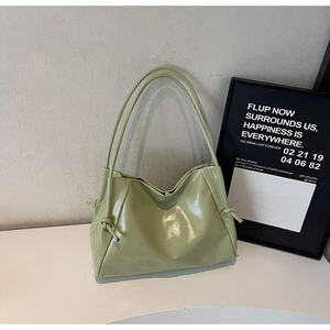Detail of light green glossy tote bag featuring unique side knots and soft texture