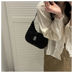 Side view of black crescent underarm bag with silver buckle on a stylish model