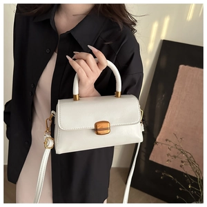 Detail of white vintage crossbody bag with gold square buckle and leather texture