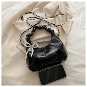 Detailed macro view of black pleated cloud bag with elegant pearl bow charm and chain strap