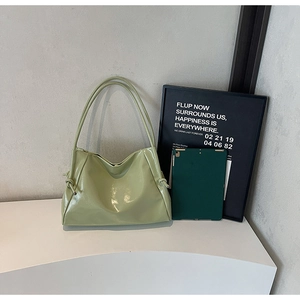 Close-up of a light sage green patent leather tote bag with knot detail on the side
